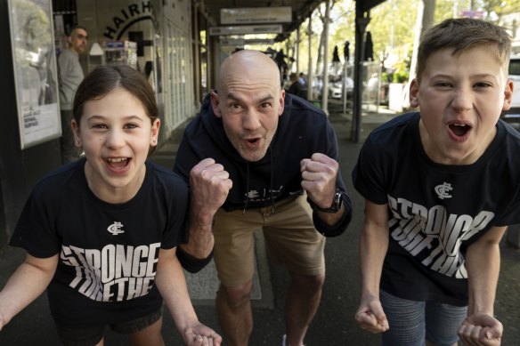 Blues fans Shane Britter with his kids Charlie, 9, and Harvey, 11, on Lygon Street in Carlton.
