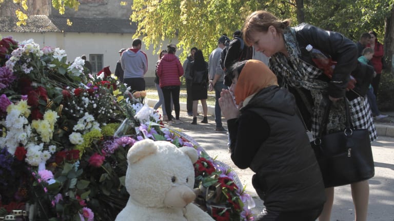 A woman prays near a memorial to the people killed during an attack in the vocational college in Kerch, Crimea. 