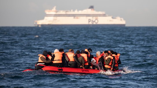 Migrants packed tightly onto a small inflatable boat bail water out as they attempt to cross the English Channel near the Dover Strait.