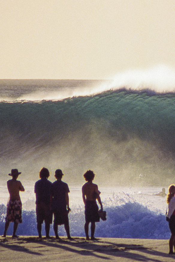 Oahu, Hawaii, January 1999: onlookers and a lone paddler take in the majesty of a fresh swell as it hits the first reef of the infamous Pipeline. The viewing platform is so close that it can feel almost as immersive as being in the water.