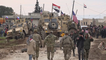 Russian, Syrian and other forces gather next to an American military convoy stuck in the village of Khirbet Ammu, east of Qamishli city, Syria.