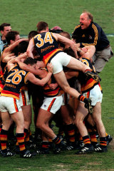 Coach Malcolm Blight jumps over the back of players after the Crows win.