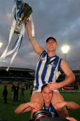 John Longmire, with the 1999 AFL premiershhip cup, sits on teammate Martin Pikeâ€™s shoulders.