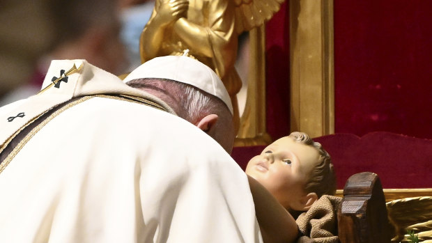 Pope Francis kisses a statue of Baby Jesus as he celebrates Mass on Christmas Eve, at St Peter's basilica at the Vatican.