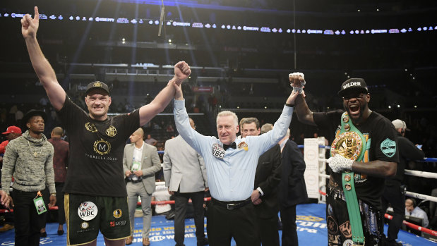 Honours even:  Tyson Fury poses with Deontay Wilder and referee Jack Reiss after the split-decision result.