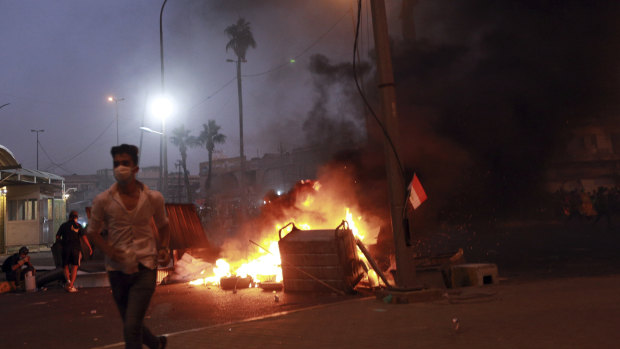 Protesters set fires while security forces take aim at them with guns and tear gas in Baghdad.
