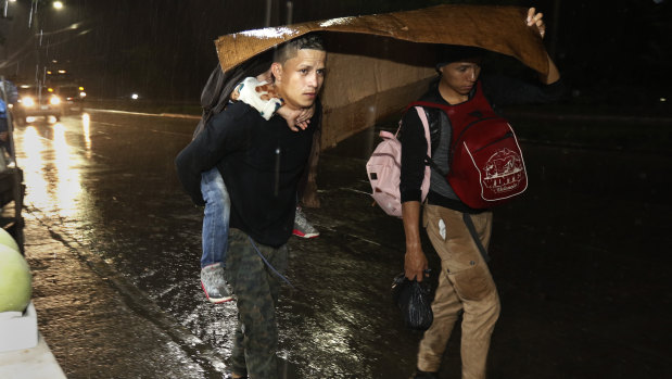 Migrants begin their journey towards the distant United States under a steady rain as a caravan of several hundred sets off walking from a main bus station in San Pedro Sula on Monday.