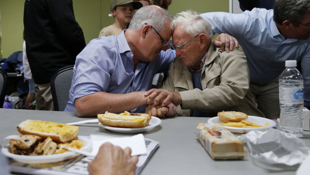 Scott Morrison comforts 85-year-old Owen Whalan of Half Chain road during a visit to Club Taree Evacuation Centre in Taree.