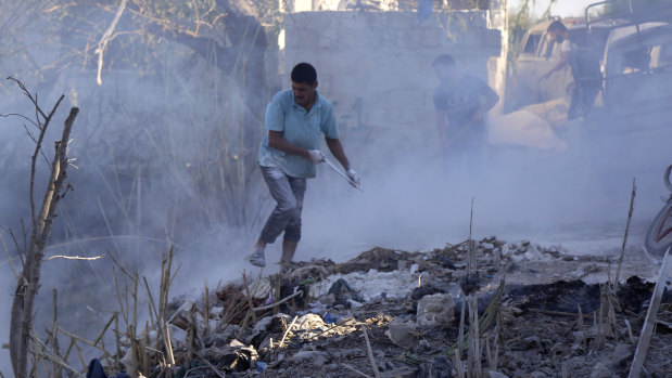 Syrians use dirt to put out a fire at the scene of a reported air strike in the district of Jisr al-Shughur, in the Idlib province, on September 4.