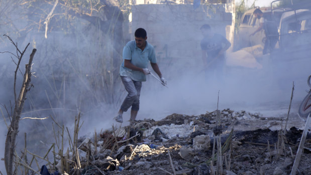 Syrians use dirt to put out a fire at the scene of a reported air strike in the district of Jisr al-Shughur, in the Idlib province, on September 4.