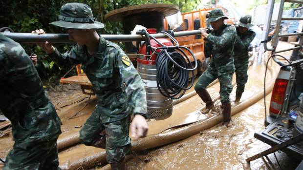Soldiers carry a pump to help drain the rising flood water.