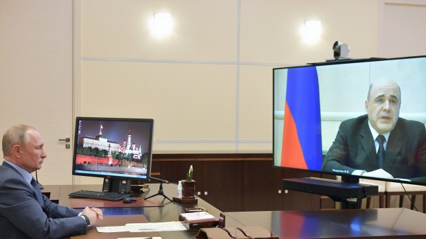 Russian Prime Minister Mikhail Mishustin (on screen) told President Vladimir Putin in a video call on Thursday that he had tested positive for COVID-19.