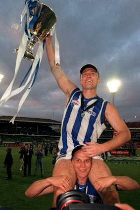 John Longmire, with the 1999 AFL premiershhip cup, sits on teammate Martin Pike’s shoulders.