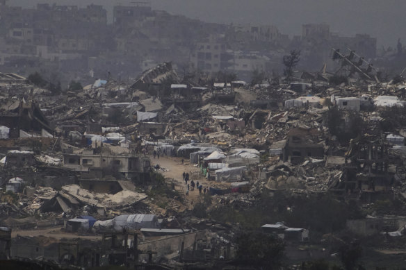 People seen from southern Israel on Thursday walk surrounded by buildings destroyed during the Israeli air and ground offensive in the Gaza Strip.