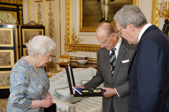 The Queen watches on as Australia’s then high commissioner to the UK Alexander Downer presents the insignia to Prince Philip.