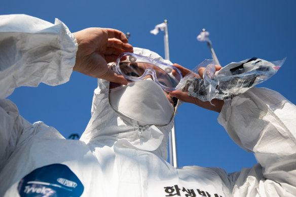A South Korean soldier adjusts his goggles before setting off on a disinfecting mission as part of South Korea's multi-billion dollar coronavirus blitz.