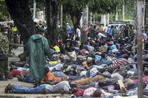 Police force passengers to the ground at the ferry terminal in Mombasa, Kenya on Friday.