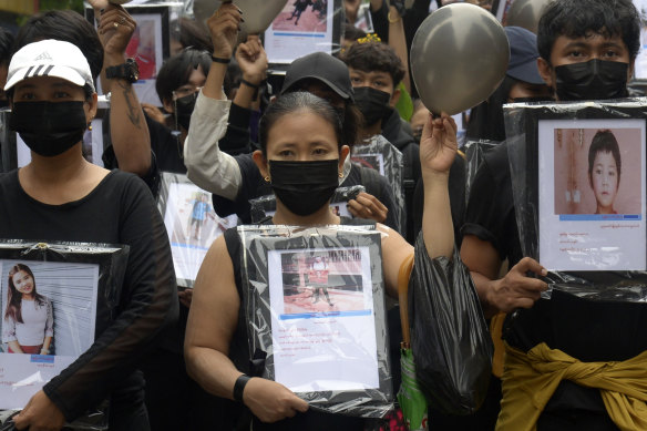 Anti-coup protesters holding pictures of those who died during a protest offer prayers for them.