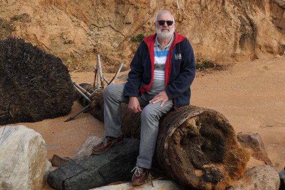 Coastal engineer Angus Gordon sits on the trunk of a tree recently dislodged from a beach-front property at Narrabeen. 