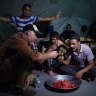 Michael Bachelard, left, eats watermelon off a dagger with Iraq’s Golden Division soldiers in their Mosul barracks on June 29, 2017.