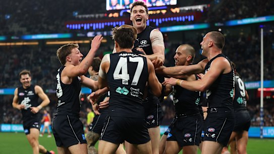 Harry Dean is swamped by teammates after kicking his first AFL goal.