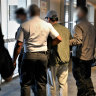 Binjun Xie is escorted to a plane after being arrested.