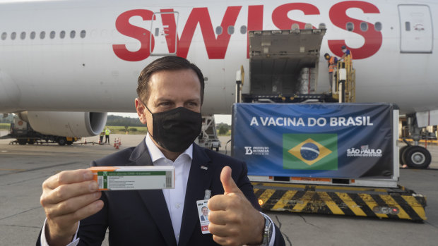 Sao Paulo Governor Joao Doria flashes a thumbs up next to a container carrying the experimental CoronaVac after it was unloaded from a cargo plane arriving from China on December 3.