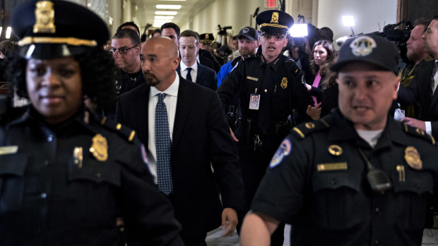 Mark Zuckerberg, centre, emerges from the second day of hearing under heavy security.