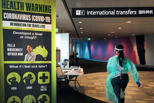 A staff member in protective medical clothing moves through the arrivals area at Brisbane International Airport.