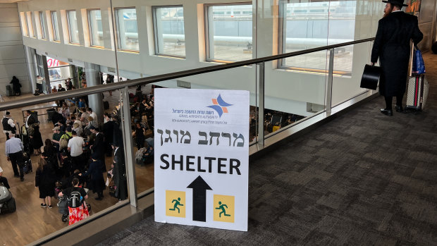 A “shelter” sign is displayed as people wait to board flights at Ben Gurion Airport near Tel Aviv on Monday.