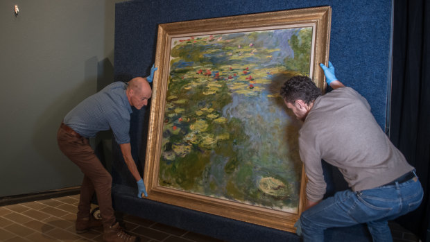 National Gallery of Australia installers Ben Taylor (left) and Chris Burton hang Monet's Water Lilies.