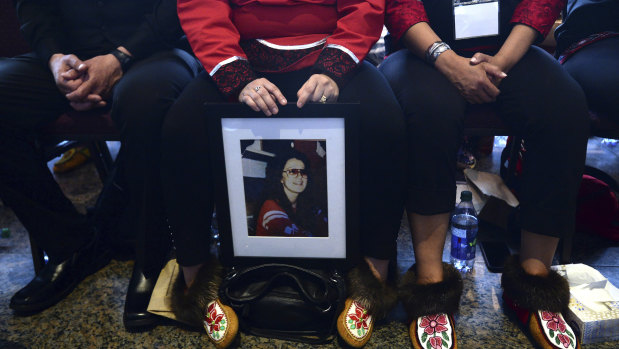 A woman holds a photo of a lost family member at the closing ceremony for the inquiry.
