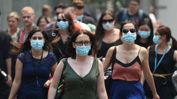People wear face masks to protect from smoke haze as they cross a busy street in Sydney's CBD. 
