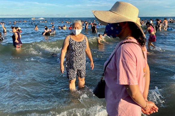 Women wearing face masks stand on a beach in Vung Tau city, Vietnam.