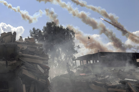 Rockets are fired from the Gaza Strip toward Israel over destroyed buildings following Israeli airstrikes on Gaza City.