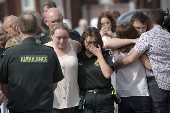 Emergency personnel comfort members of the public near the scene in Hart Street, where three children died in the knife attack.