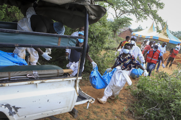 Police and local residents load the exhumed bodies of victims of a religious cult into the back of a truck in the village of Shakahola, near the coastal city of Malindi.
