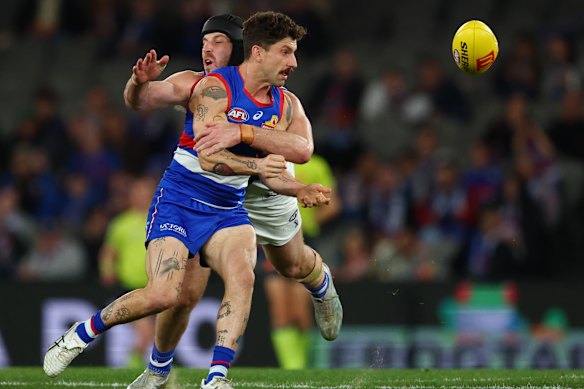 Tom Liberatore of the Bulldogs handballs despite pressure from the Roos.