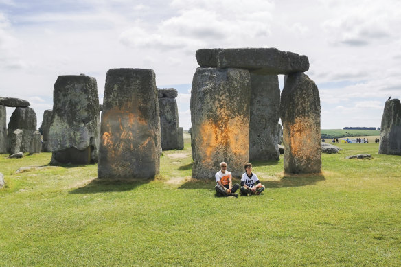 Just Stop Oil protesters sit after spraying an orange substance on Stonehenge.
