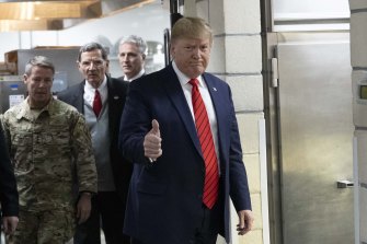 President Donald Trump gives the thumbs up as he prepares to serve dinner during a surprise Thanksgiving Day visit to the troops.