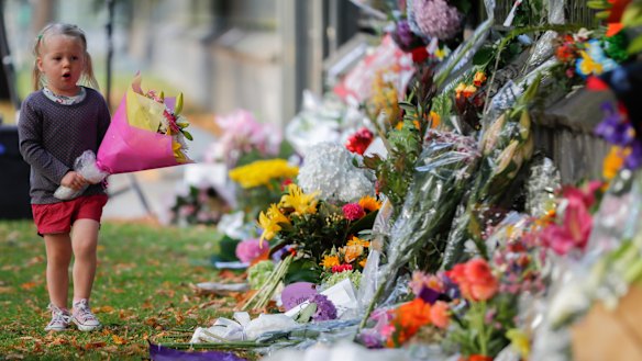 A girl carries flowers to a memorial wall following the mosque shootings in Christchurch, which left 50 dead and 39 wounded.