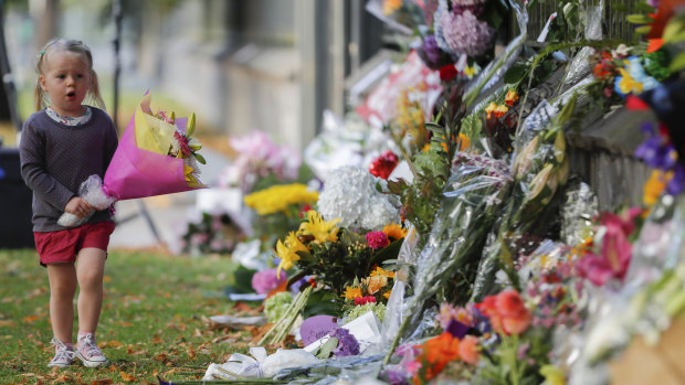 A girl carries flowers to a memorial wall following the mosque shootings in Christchurch, which left 50 dead and 39 wounded.