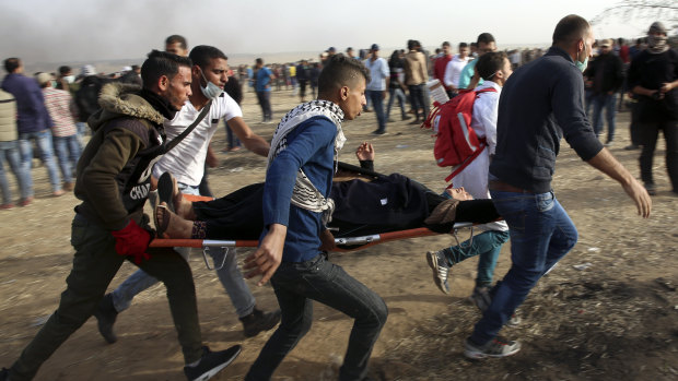 Palestinian protesters evacuate a wounded woman during clashes with Israeli troops along Gaza's border with Israel on Friday.