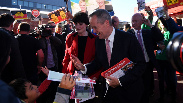 Bill Shorten high-fives a boy while on the last-minute campaign trail with Labor's candidate for Higgins, Fiona McLeod.