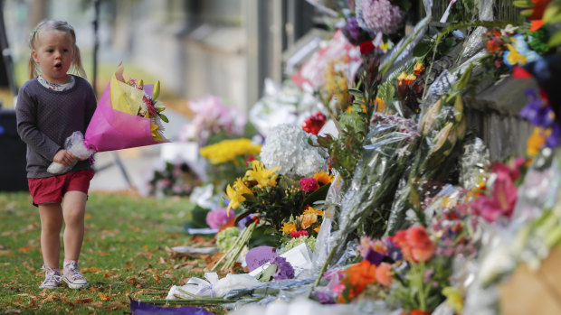A girl carries flowers to a memorial wall following the mosque shootings in Christchurch, which left 50 dead and 39 wounded.