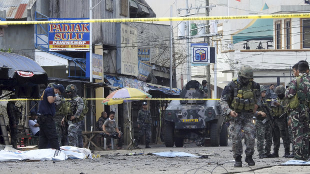 Police investigators and soldiers attend the scene in Jolo on Sunday.