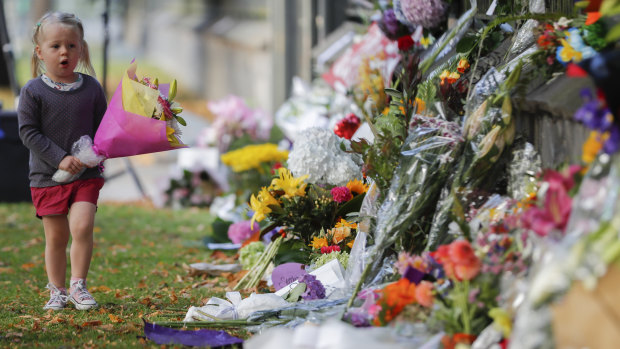 A girl carries flowers to a memorial wall following the Christchurch shootings, which left 50 dead and 39 wounded.