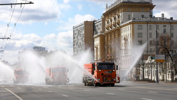 Tankers spray disinfectant on the empty Garden Ring in Moscow on Sunday, with the US embassy on the right.