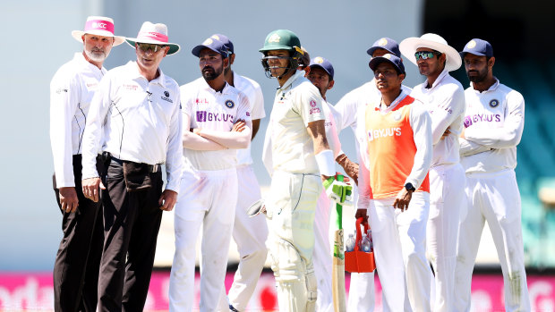 Australia captain Tim Paine stands with Indian players and umpires as police walk six men from their seats during the third Test.