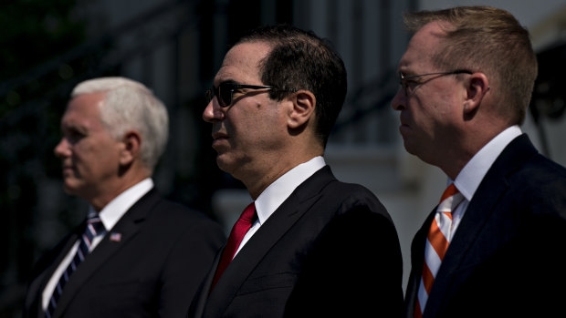 Vice President Mike Pence, Treasury Secretary Steve Mnuchin and director of the Office of Management and Budget Mick Mulvaney, watch on as Trump celebrates the economy.